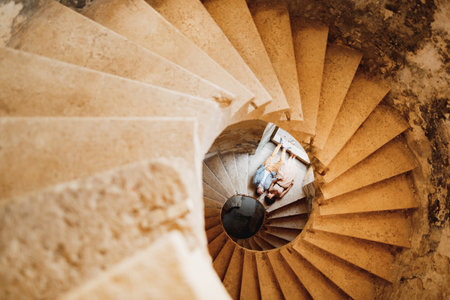 Tivat, Montenegro - 20 april 2021: Newlyweds lie holding hands on the spiral staircase of the...