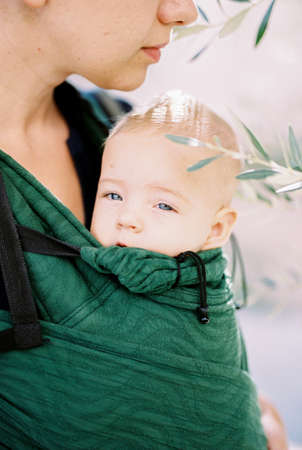 Sleepy baby in a mother sling. Portrait