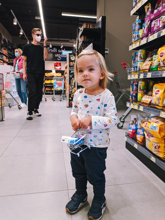 Budva, Montenegro - 01.08.22: Little girl with a toy grocery cart stands in a supermarketのeditorial素材