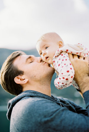 Dad lifts the baby above his head and kisses him on the cheek. Portraitの写真素材