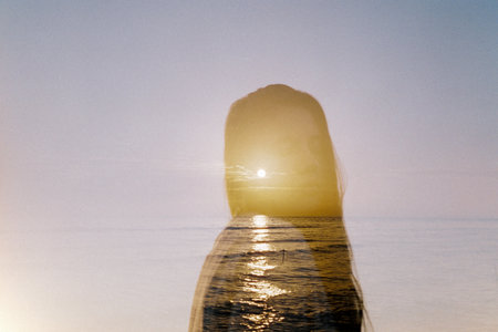 Sun on the horizon through the silhouette of a girl with long hair