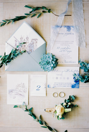 Wedding invitations on the table next to wedding rings and flowers