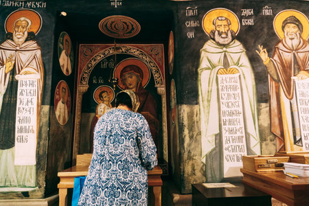 Tivat, Montenegro - 25.08.2022: Woman prays in front of the icons in the Ostrog monastery....