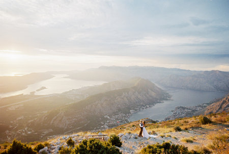 Bride and groom stand on a mountain against the backdrop of the panorama of Kotor Bayの写真素材