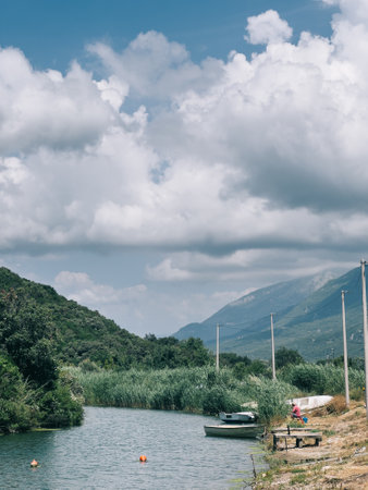 Fishing boats lie on the banks of the river overgrown with reeds at the foot of the mountainsの写真素材