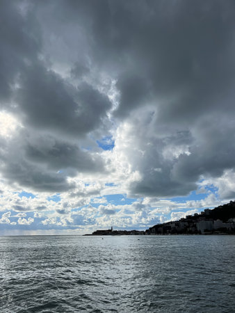 Thunderclouds in the sky above the sea at the foot of the mountainsの写真素材