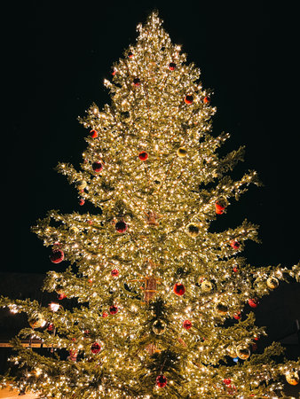 Christmas tree decorated with colorful balls with luminous garlands against a dark sky