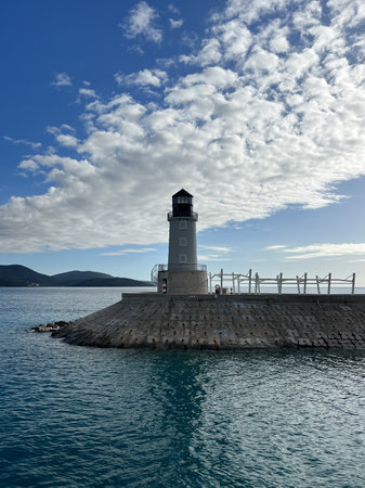Lighthouse on a breakwater against a cloudy skyの写真素材