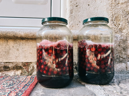 Ripe cherries are covered with sugar in glass jars under lidsの写真素材
