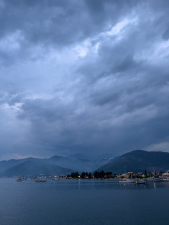 Falling dusk on a bay with sailing yachts at the foot of a mountain rangeの写真素材
