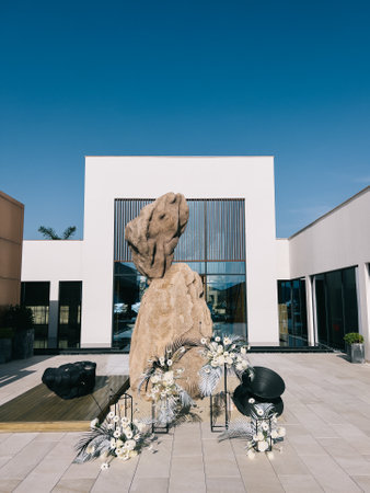 Herceg Novi, Montenegro - 09.08.2022: Bouquets of flowers stand on metal stands near a stone sculpture in the courtyard of the hotelのeditorial素材
