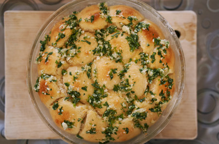 Ruddy buns sprinkled with grated garlic and herbs lie in a glass dish. Top viewの写真素材