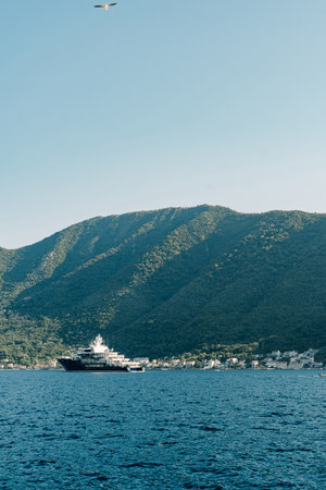 Passenger ship sails on the blue sea against the backdrop of a green mountain rangeの写真素材