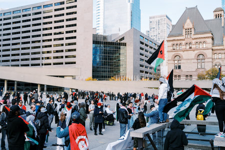 Toronto, Canada - 28 October 2023: Anti-war march in Toronto by Palestinians against Israels aggression in Gaza. Citys peaceful protest against Israel-HAMAS war. Protesters wave flagsのeditorial素材