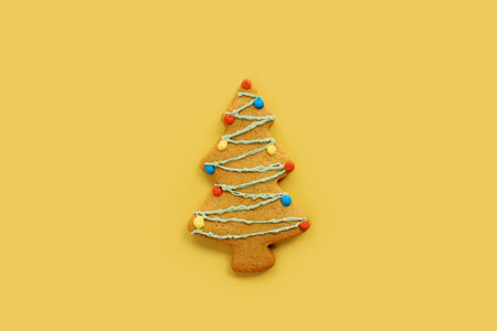 Christmas tree cookie with colorful garlands on a yellow backgroundの写真素材