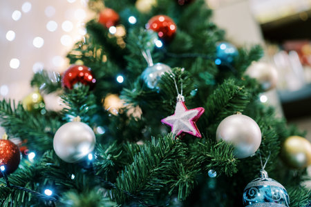 Pink star next to silver and blue balls hangs on a Christmas treeの写真素材