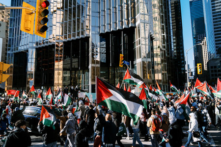 Toronto, Canada - 28 October 2023: Anti-war march in Toronto by Palestinians against Israels aggression in Gaza. Citys peaceful protest against Israel-HAMAS war. Protesters wave flagsのeditorial素材