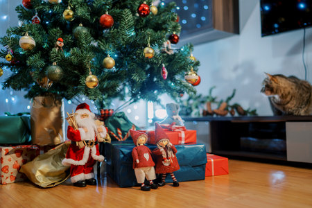 Figures of elves stand near Santa near colorful gifts under the Christmas treeの写真素材