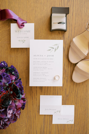 Engagement ring lies on the invitation next to the bouquet, the bride shoes and the groom tieの写真素材