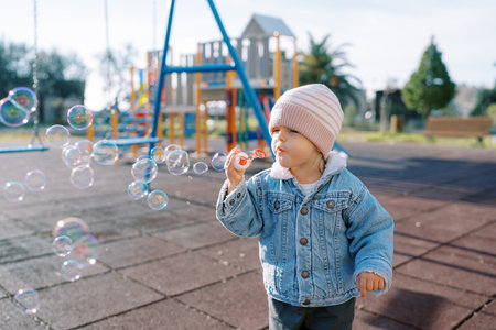 Little girl blowing soap bubbles on the playgroundの写真素材