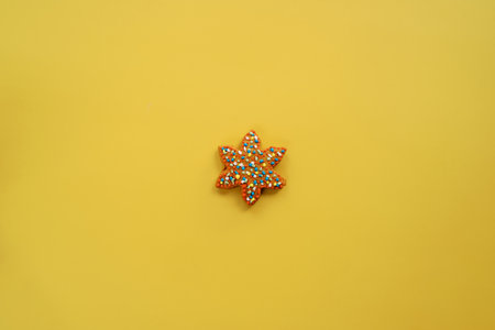 Glazed colorful gingerbread star lies on a yellow backgroundの写真素材