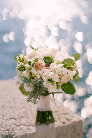Bride bouquet stands on the shore against the backdrop of the shining sea. Blurの写真素材