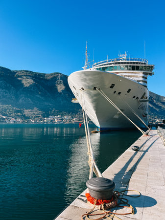 Kotor, Montenegro - 25 december 2022: Large ship is moored to the mooring bollards at the pier against the backdrop of the mountainsのeditorial素材