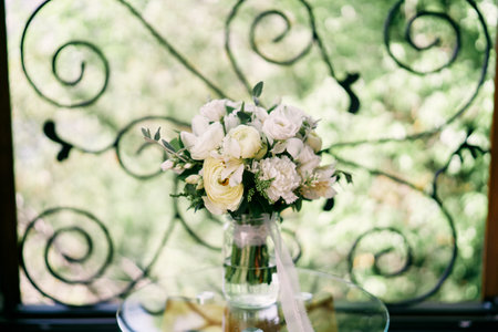 Bridal bouquet stands in a glass jar near the forged fence on the balconyの写真素材