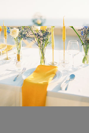 Yellow napkin lies on a plate on a set table with bouquets of flowersの写真素材