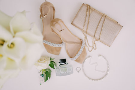 Wedding ring lies on a white table near the bride shoes, handbag and perfume. Top viewの写真素材