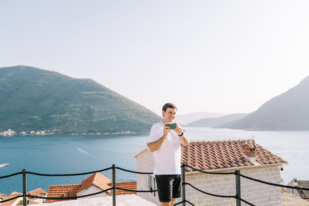 Man shoots with a smartphone while standing on a platform above the sea