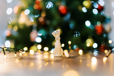 Figurine of a cat on the table in the light of colorful lights on the Christmas tree. Blurの写真素材