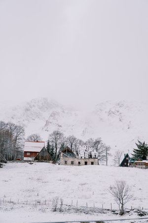 Snow-covered house under construction in a small village at the foot of the mountains