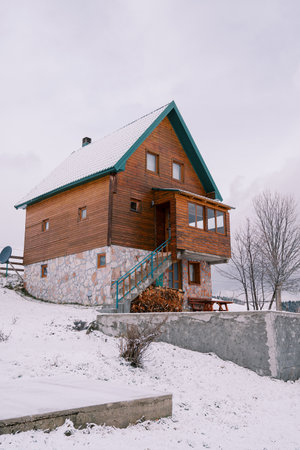 Wooden two-story house with a woodpile in a snowy village