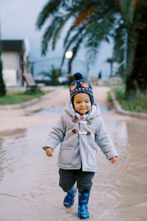 Little smiling girl walking through the puddlesの写真素材