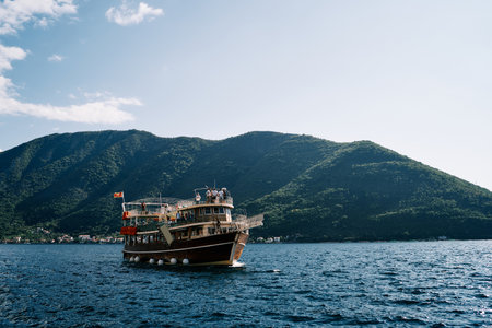 Large double-deck excursion yacht sails along the mountainous coastlineの写真素材