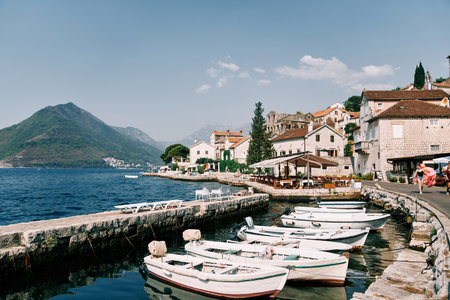 Row of white fishing boats is moored along the Perast promenade. Montenegroの写真素材
