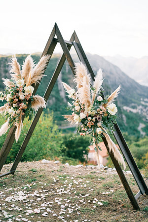 Wedding arch wigwam decorated with flowers stands on the mountainの写真素材