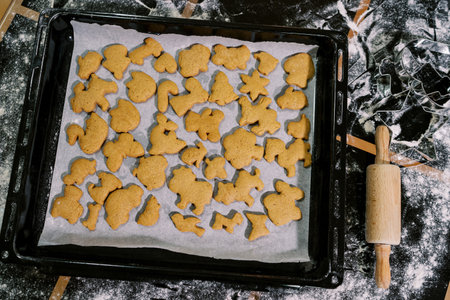 Baked Christmas cookies lie on baking paper on a tray on a floured table. Top viewの写真素材