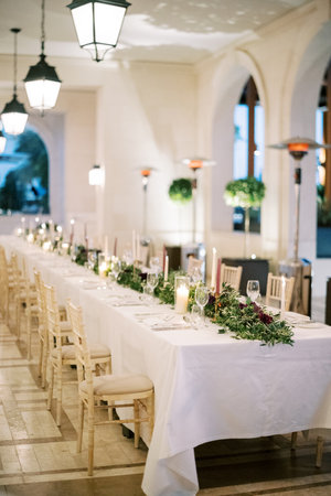 Long set table divided into two halves with flowers and lit candlesの写真素材