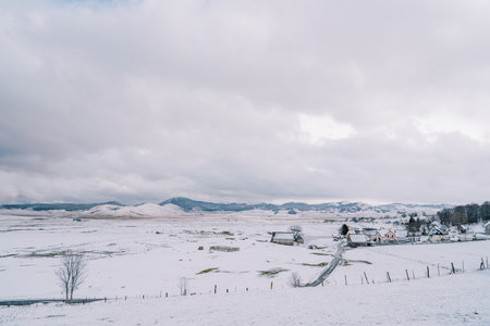 Small snowy village with pastures in a mountain valleyの写真素材