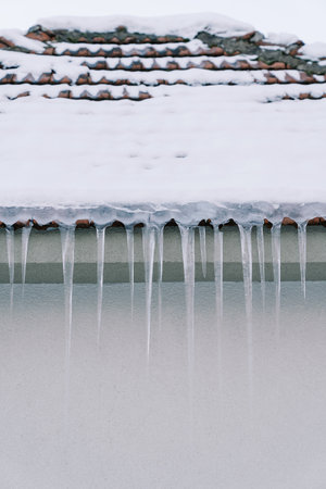 Icicles hang from the snow-covered roof of a buildingの写真素材