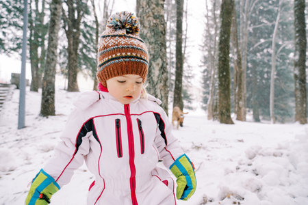 Little girl walks through a snowy forest and looks at her feetの写真素材