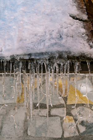 Icicles hang from the snow-covered roof of a house