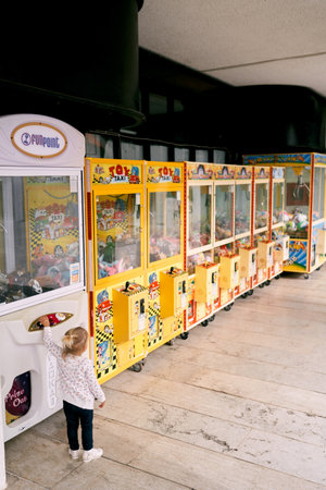 Little girl takes out a toy from a claw machine. Back viewの写真素材
