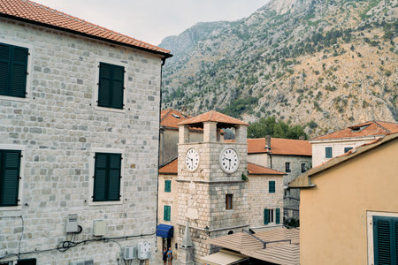 Ancient clock tower among stone houses on the square. Kotor, Montenegro