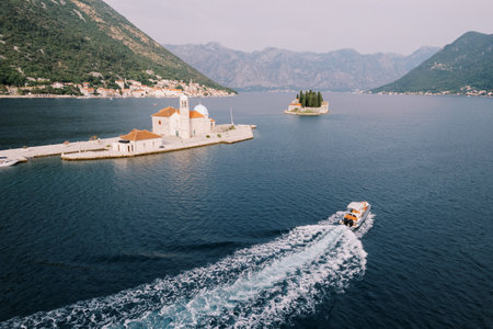 Yacht sails on the sea past the island of Gospa od Skrpjela to the island of St. George. Montenegro....