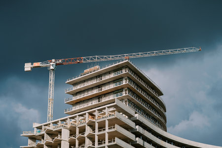 Tower crane over a skyscraper under construction against a stormy sky