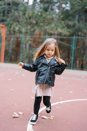 Little girl with flying hair walks on the playground