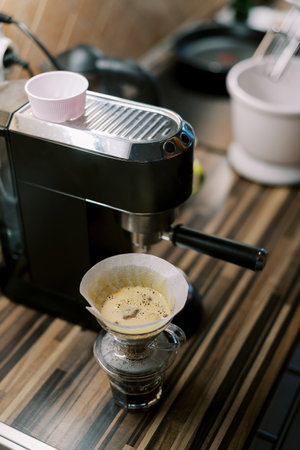 Coffee dripping through the filter of the pour over coffee maker next to the coffee machine